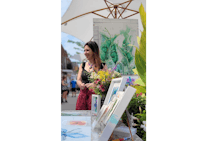 a woman standing in front of a display of paintings